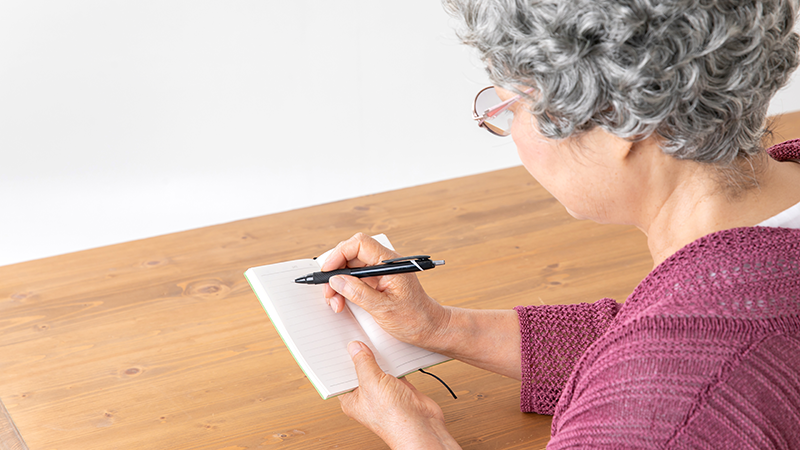 メモを書くシニア女性 