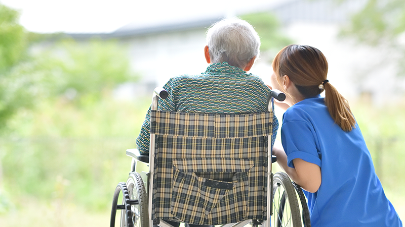 施設で過ごす車いすの高齢者とスタッフ