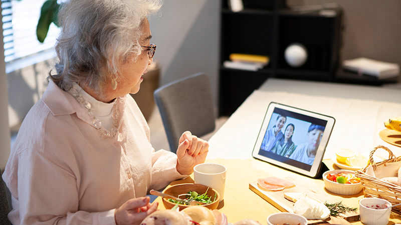 パッドを見ながら食事をする高齢女性