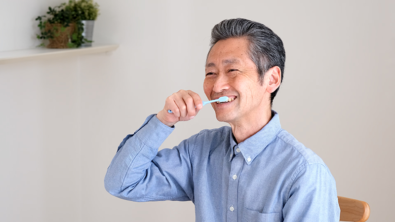 口腔衛生が気になり歯磨きをする高齢者男性
