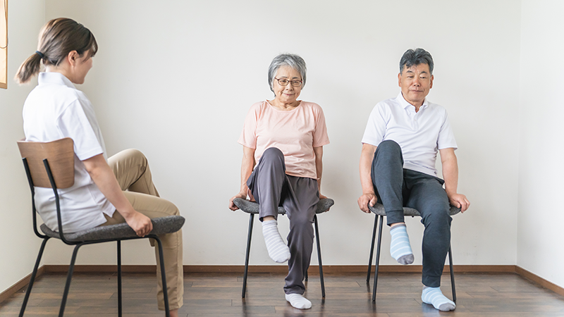 椅子に座って体操を行う高齢者