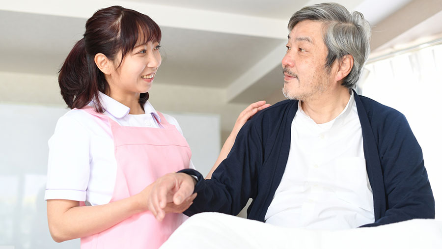 男性の肩を掴む介護士