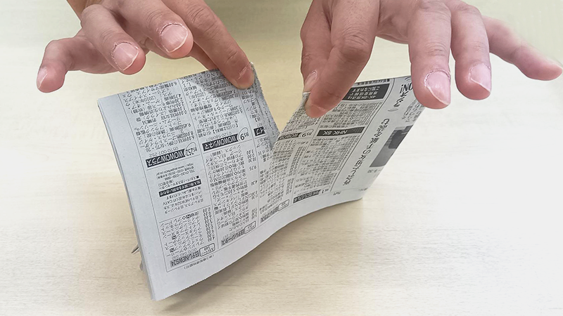 指で新聞紙をちぎる