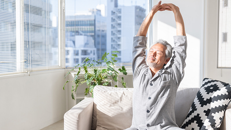 朝起きてストレッチをするシニア男性