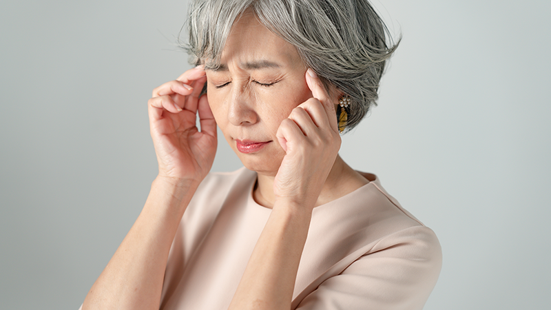 頭を抑えるシニア女性