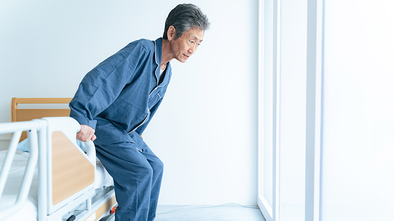 ベッドに掴まり立ち上がるシニア